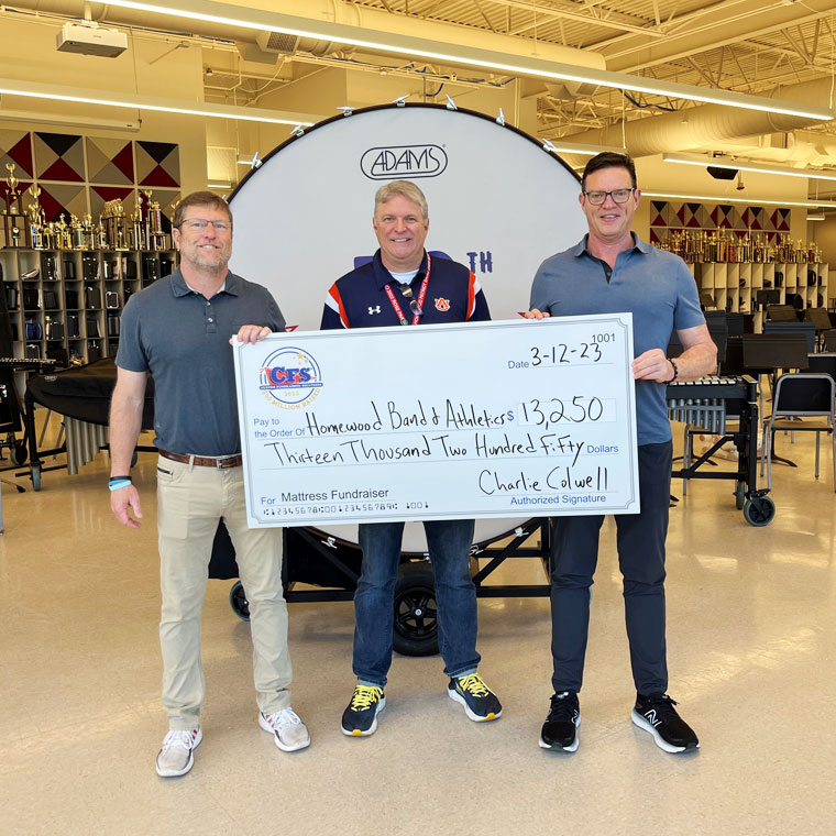 Three people holding a cheque from the mattress fundraiser